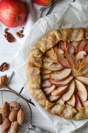 Delicious apple galette and pecans on white wooden table, flat lay
