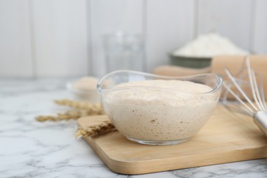Photo of Leaven and ears of wheat on white marble table