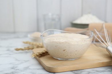 Leaven and ears of wheat on white marble table