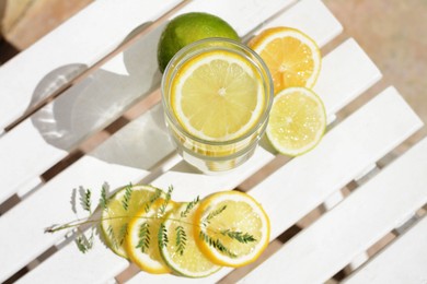 Photo of Delicious refreshing lemonade and pieces of citrus on white wooden table outdoors, above view