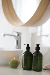 Photo of Green soap dispensers on countertop near sink in bathroom