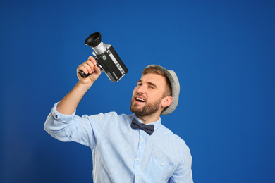 Photo of Young man with vintage video camera on blue background
