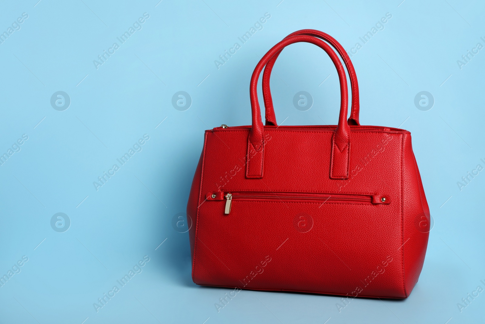 Photo of Stylish woman's bag on light blue background. Space for text