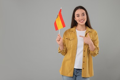Young woman holding flag of Spain on light grey background, space for text