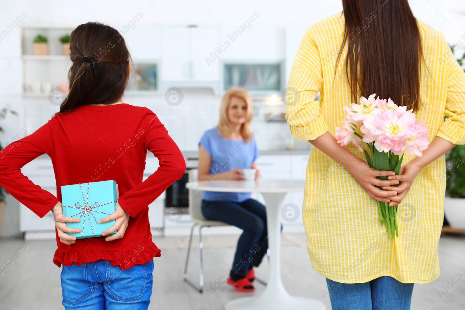 Photo of Woman and her daughter congratulating granny in kitchen. Happy Mother's Day