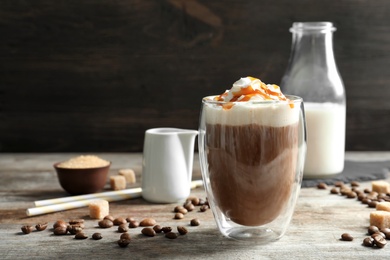 Glass of coffee with caramel topping on wooden table