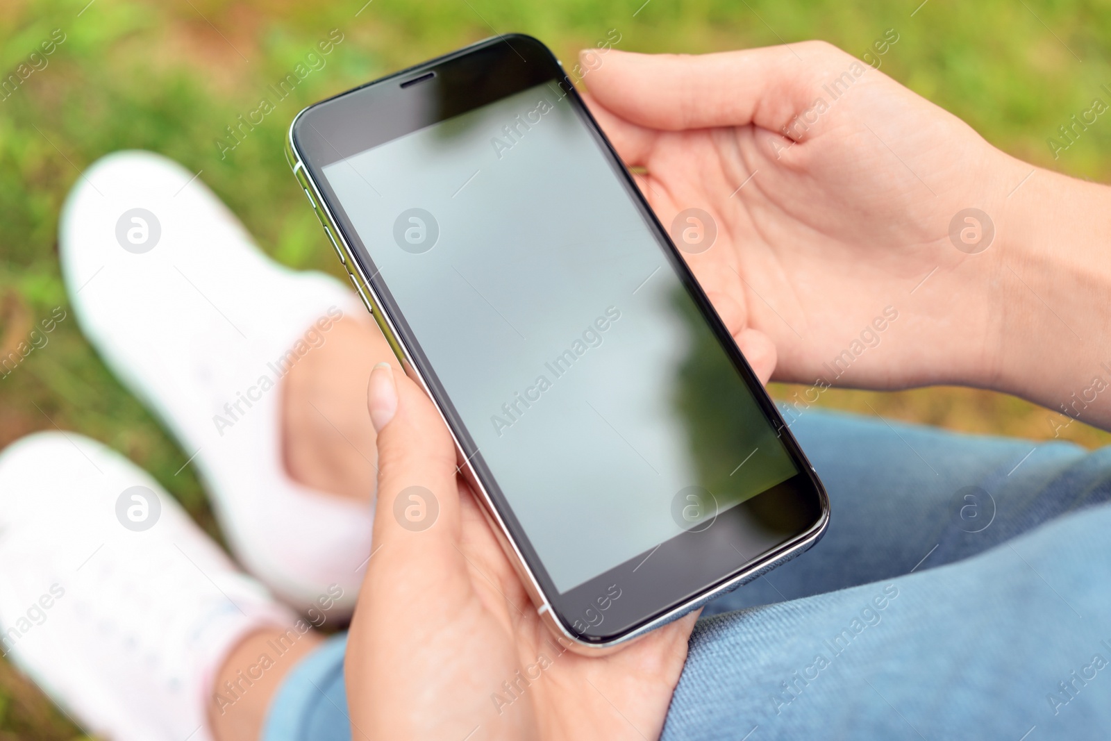 Photo of Woman holding modern smartphone outdoors. Mock up with space for text