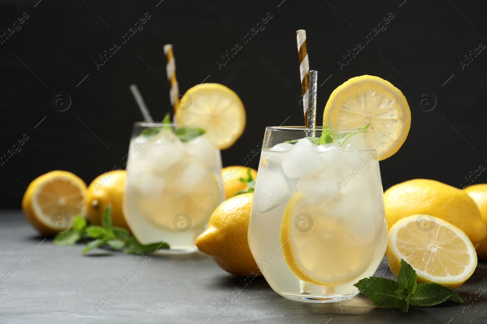 Photo of Natural lemonade with mint on grey table against black background, space for text. Summer refreshing drink
