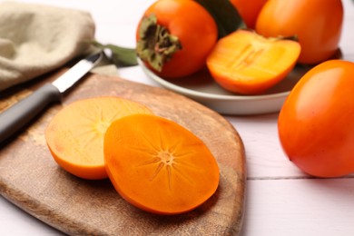 Photo of Delicious ripe juicy persimmons on wooden board, closeup