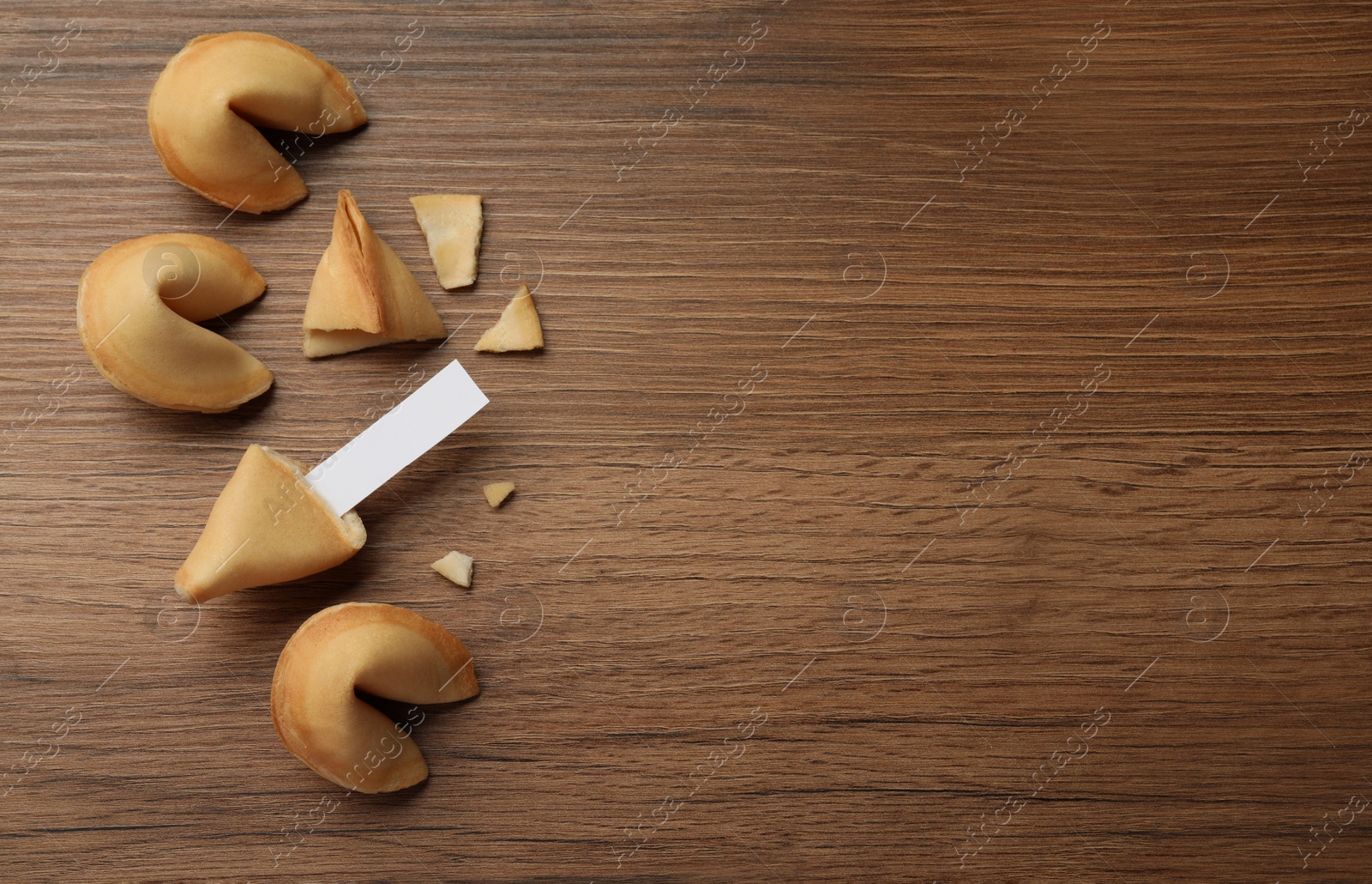 Photo of Tasty fortune cookies and paper with prediction on wooden table, flat lay. Space for text