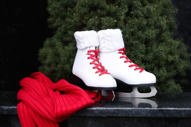 Red knitted scarf and pair of ice skates on stone step outdoors