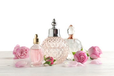 Different perfume bottles and flowers on light background