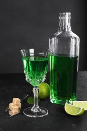 Photo of Absinthe, spoon, brown sugar and lime on black table. Alcoholic drink
