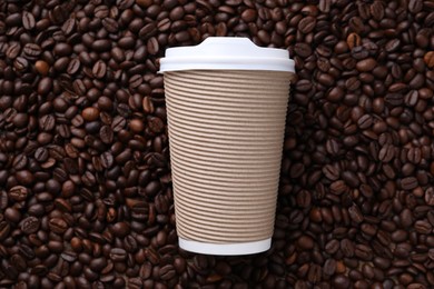 Photo of Coffee to go. Paper cup on roasted beans, top view