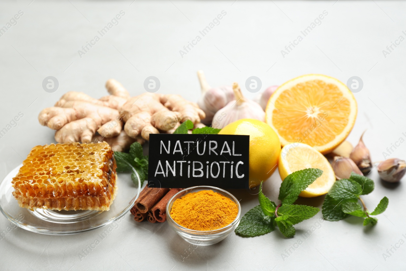 Photo of Different fresh products and card with phrase Natural Antibiotic on grey table