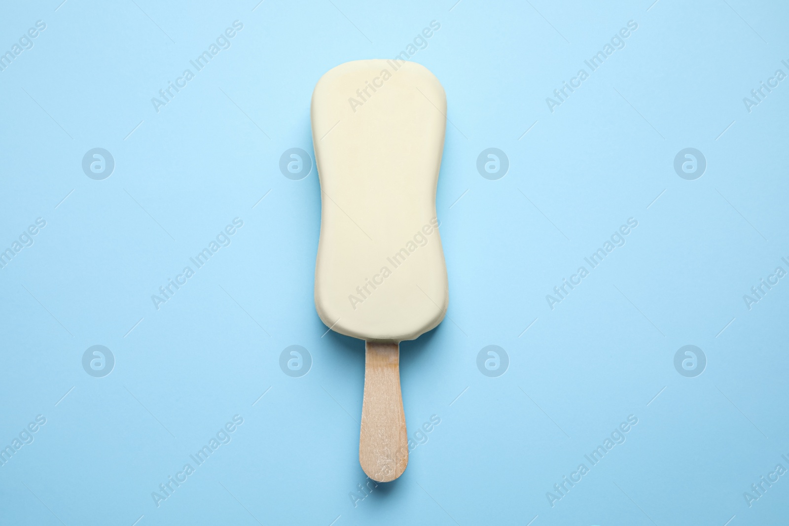 Photo of Ice cream with glaze on light blue background, top view