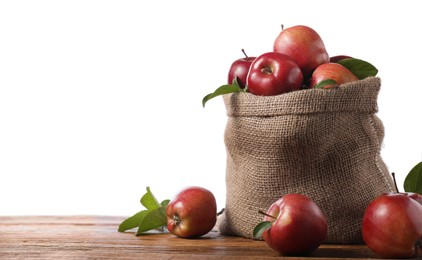 Photo of Ripe red apples with leaves in sack on wooden table against white background. Space for text