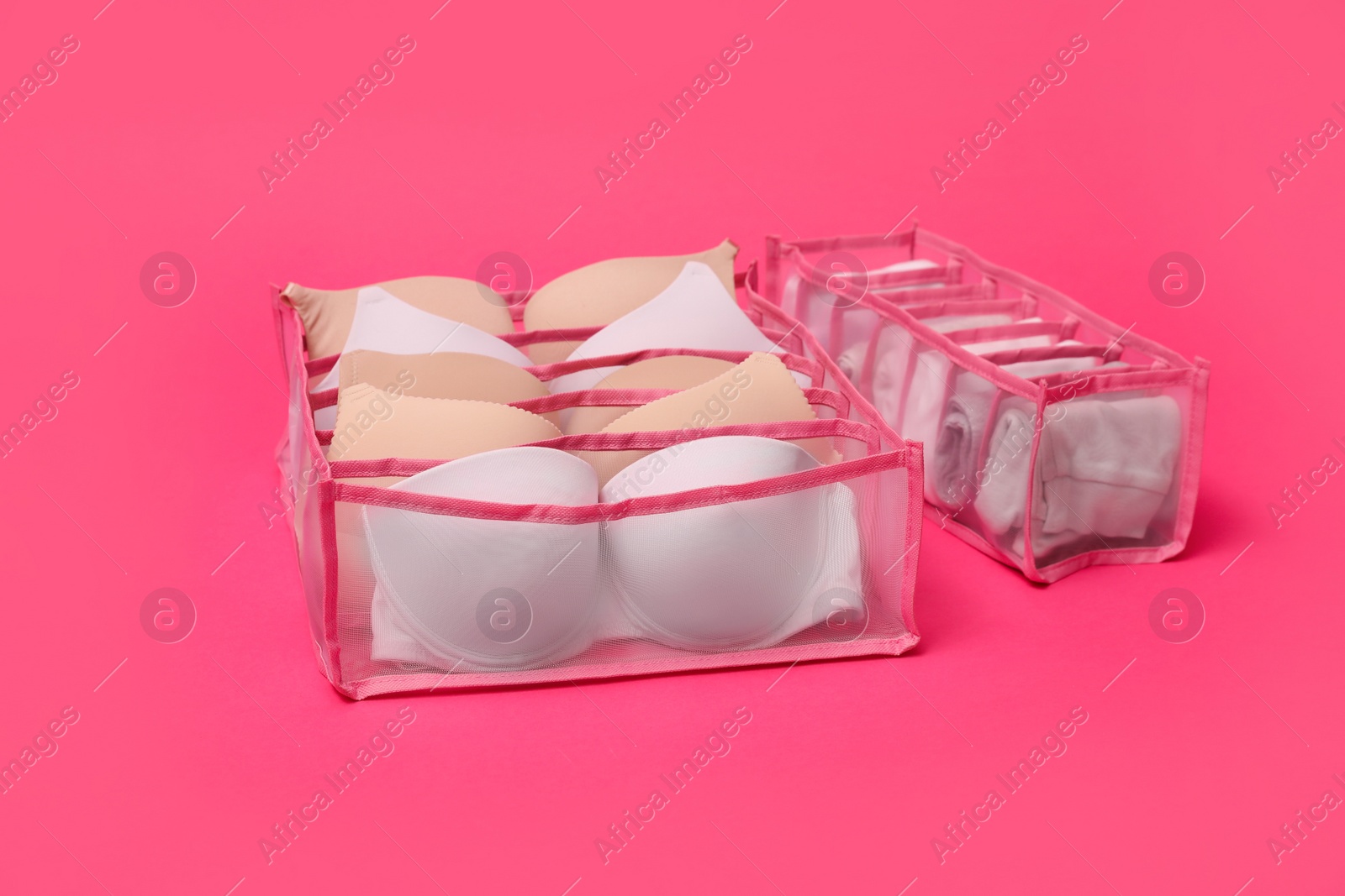 Photo of Transparent organizers with underwear on pink background