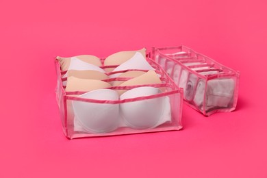 Photo of Transparent organizers with underwear on pink background