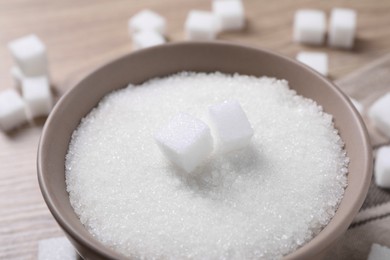 Different types of white sugar in bowl on table, closeup