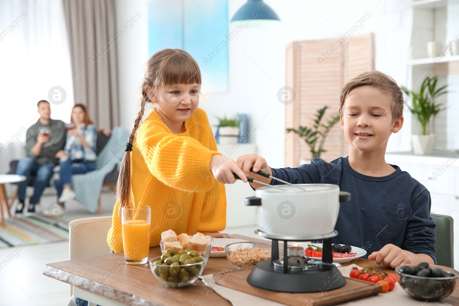 Photo of Happy kids enjoying fondue dinner at home