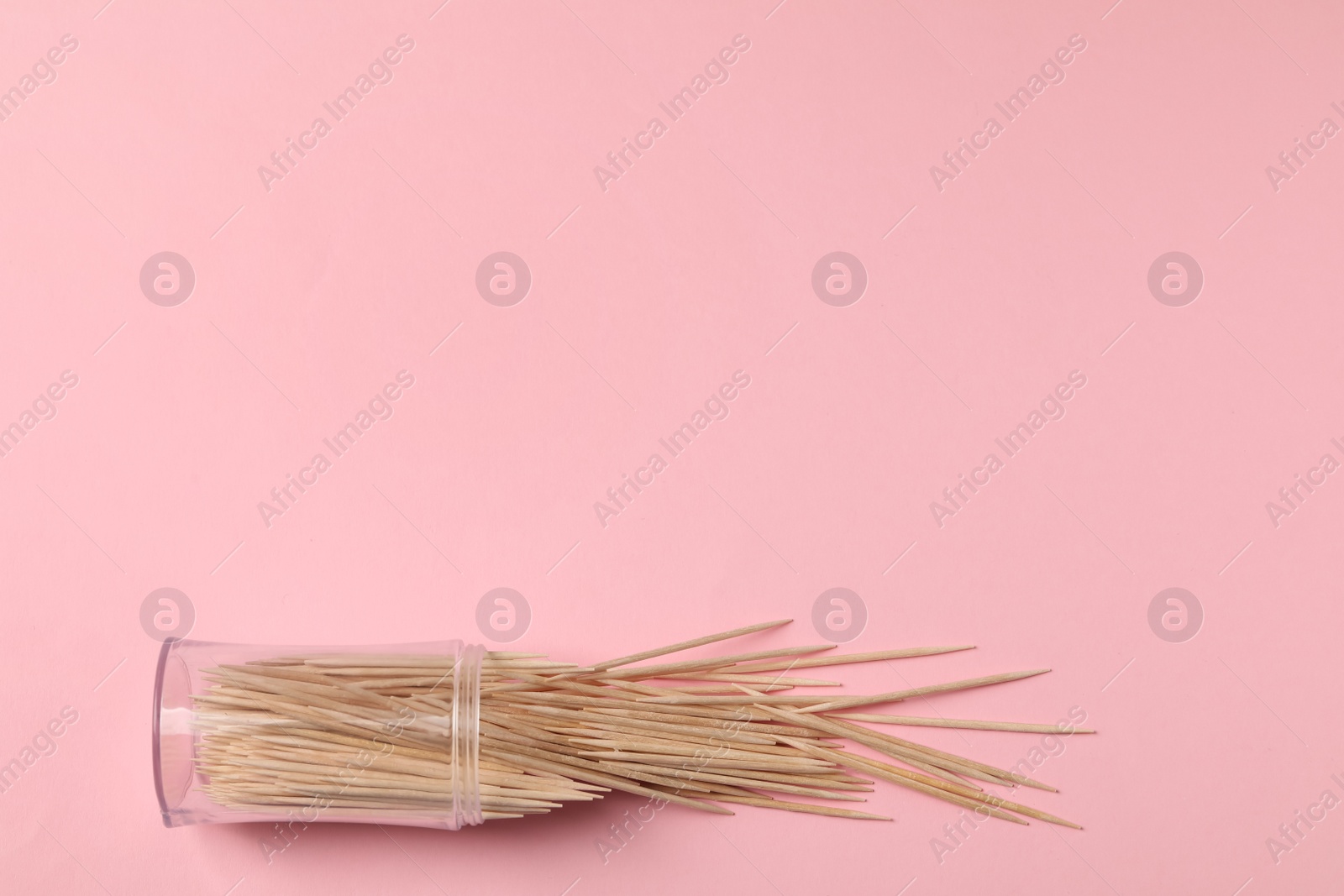 Photo of Wooden toothpicks and holder on pink background, flat lay. Space for text