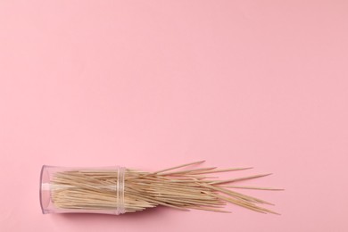 Wooden toothpicks and holder on pink background, flat lay. Space for text