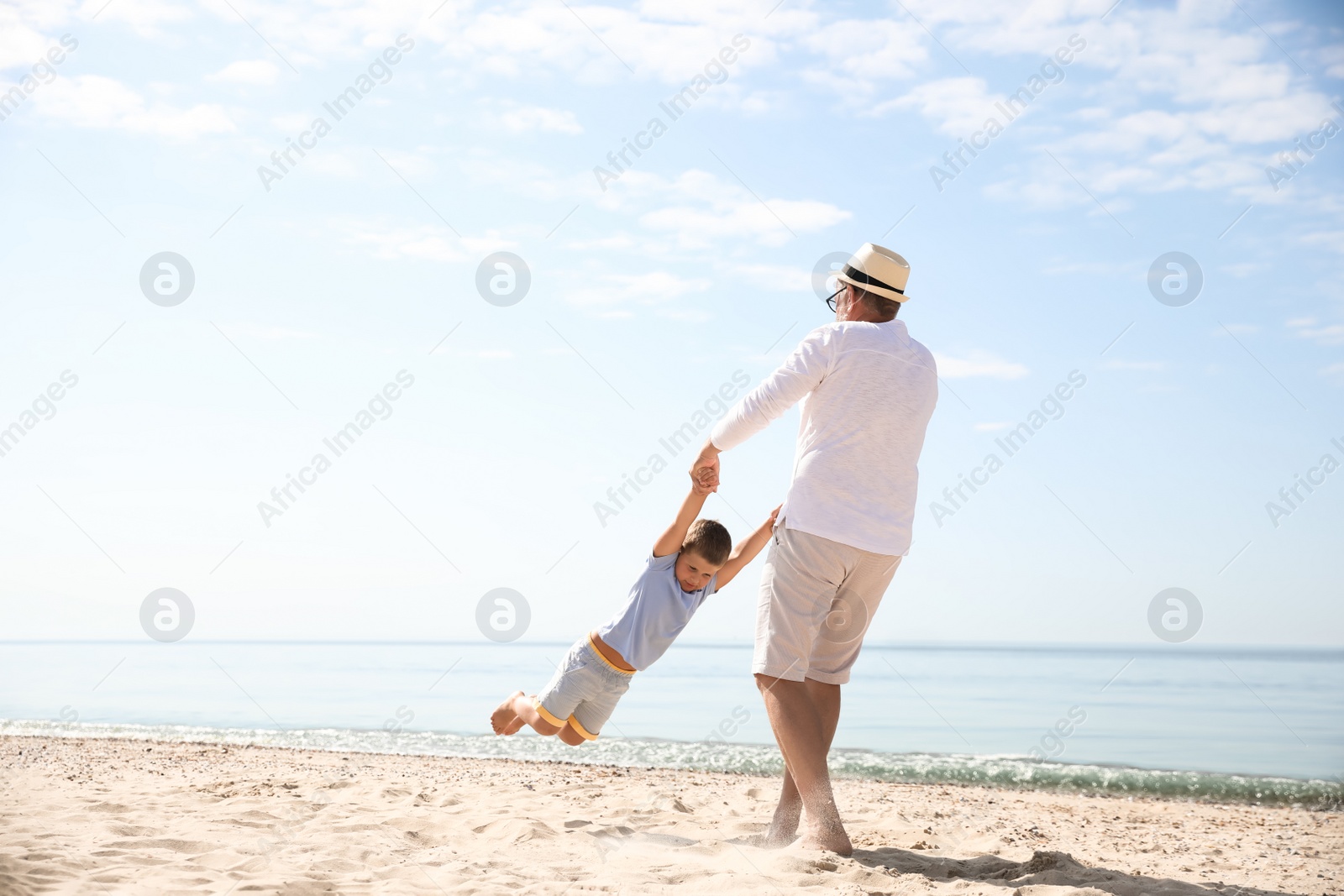 Photo of Grandfather playing with little boy on sea beach