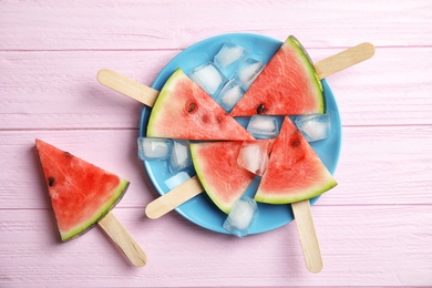 Photo of Flat lay composition with watermelon popsicles and ice cubes on wooden background