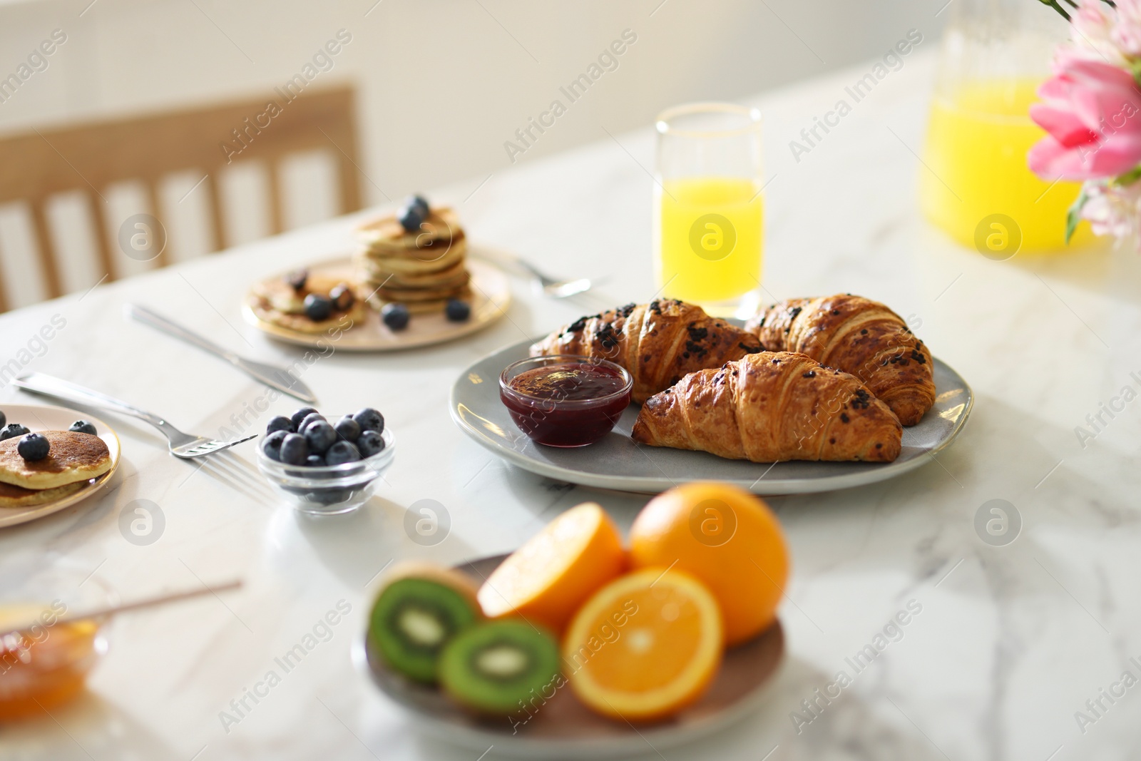 Photo of Tasty breakfast. Fresh croissants with jam on white marble table, selective focus