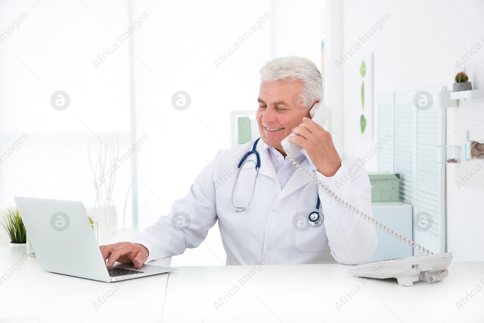 Photo of Senior male doctor working at reception desk in hospital