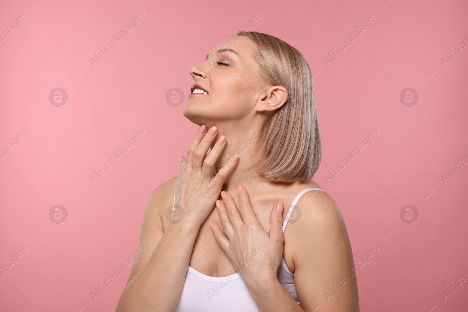 Photo of Beautiful woman touching her neck on pink background