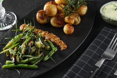 Photo of Delicious salad with tarragon, mustard and grilled potatoes served on black table