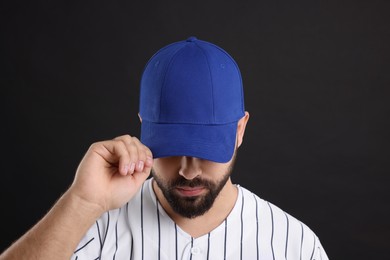 Man in stylish blue baseball cap on black background