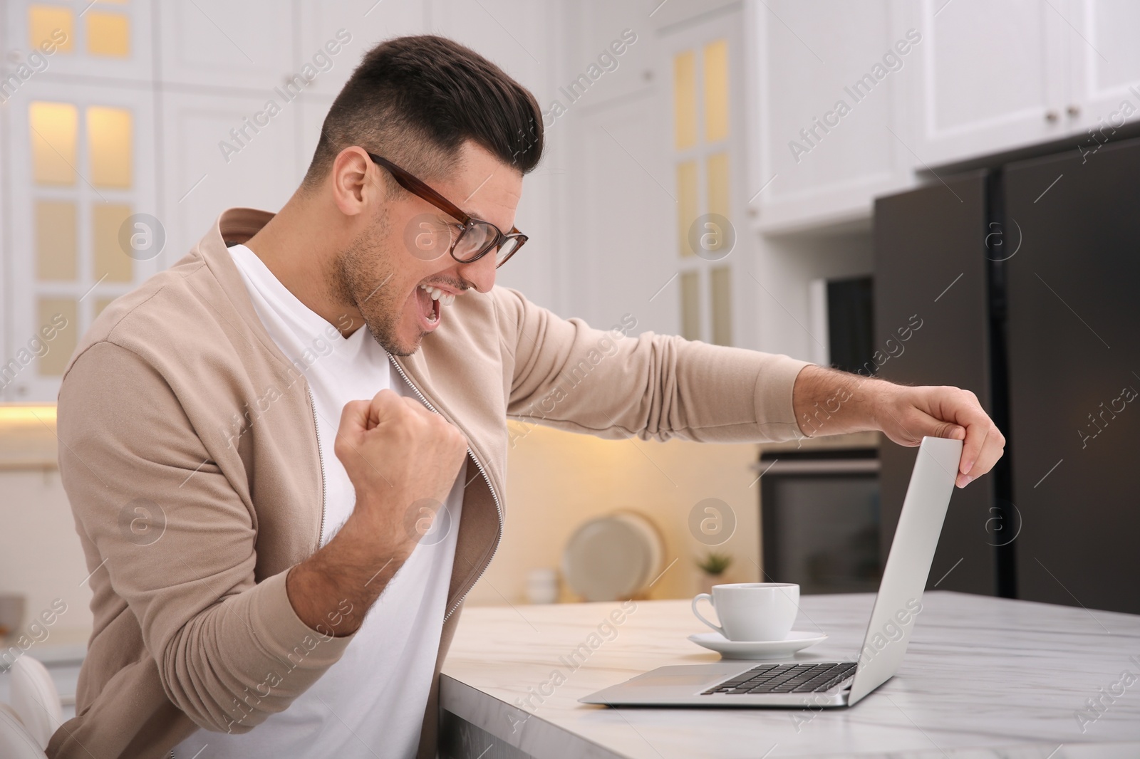 Photo of Emotional man participating in online auction using laptop at home