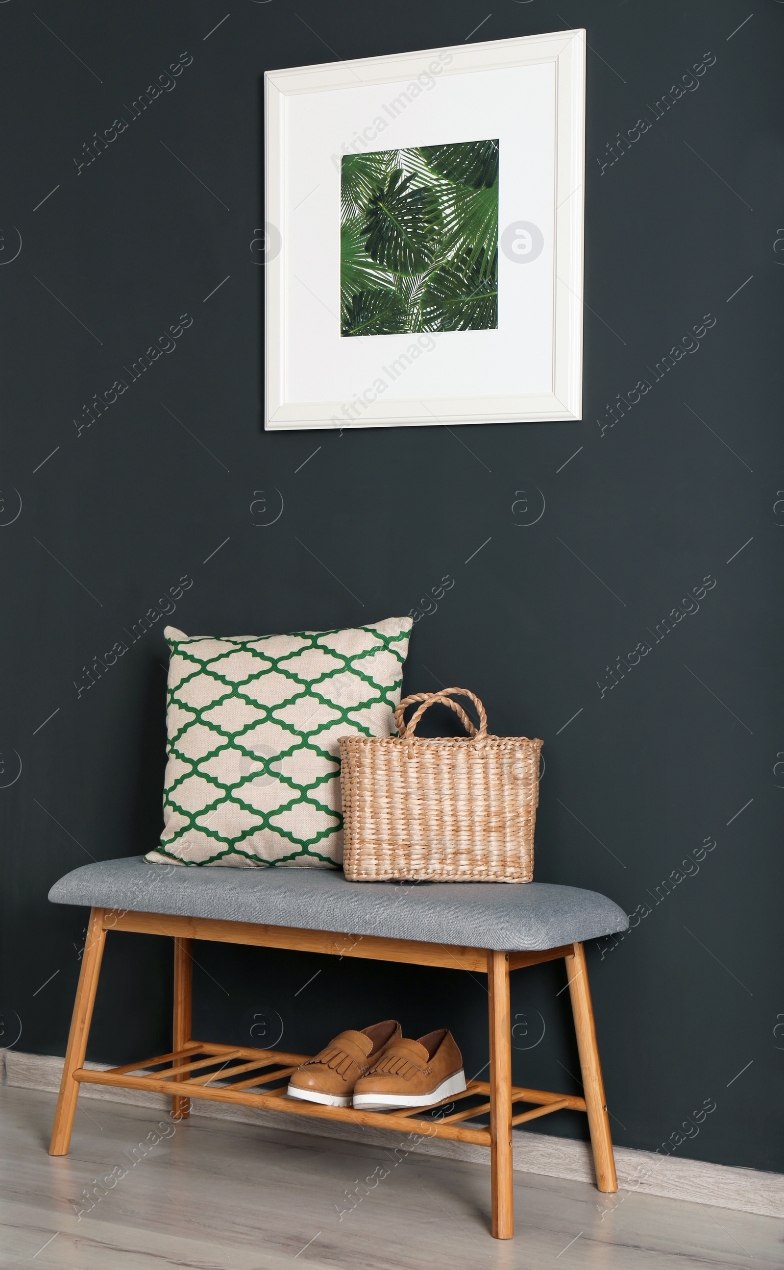Photo of Bench with pillow and bag at black wall. Interior design