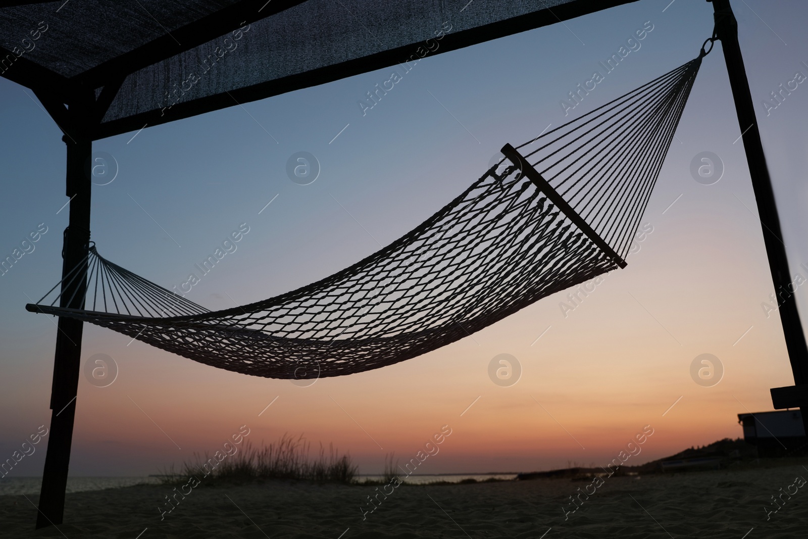 Photo of Empty hammock on beach at sunset. Time to relax