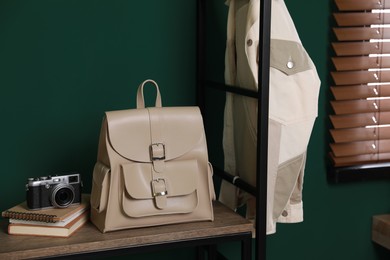 Photo of Stylish urban backpack, books and camera on shelf indoors