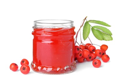 Photo of Delicious rowan jam in glass jar and berries with green leaves on white background