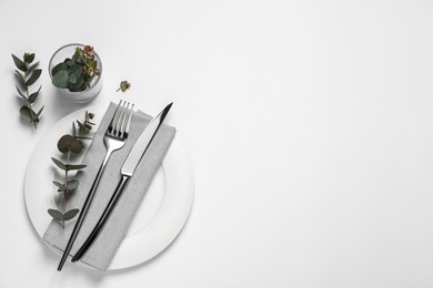 Photo of Stylish setting with cutlery and eucalyptus leaves on white background, top view. Space for text
