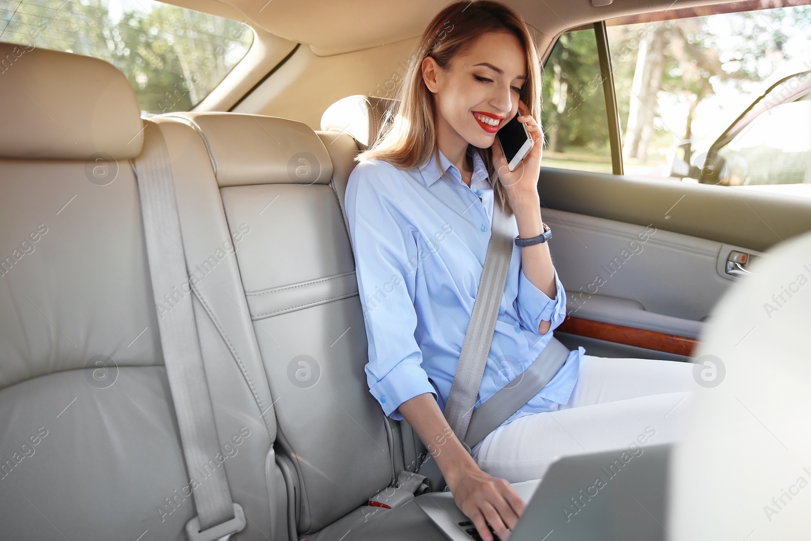 Photo of Young businesswoman with smartphone and laptop in car