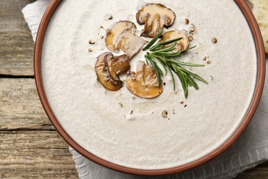 Photo of Fresh homemade mushroom soup in ceramic bowl on wooden table, top view