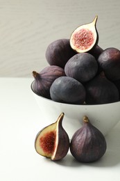 Photo of Whole and cut tasty fresh figs on white table