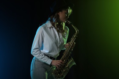 Photo of Beautiful young woman playing saxophone on dark background