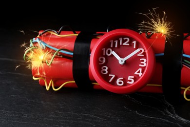 Image of Dynamite time bomb with burning wires on black table, closeup