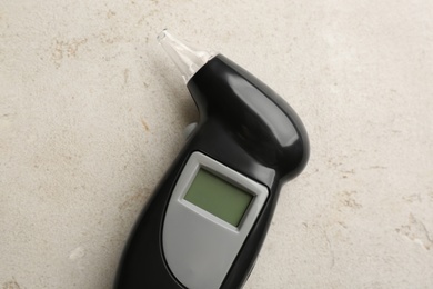 Photo of Modern breathalyzer with blank screen on light grey stone table, top view