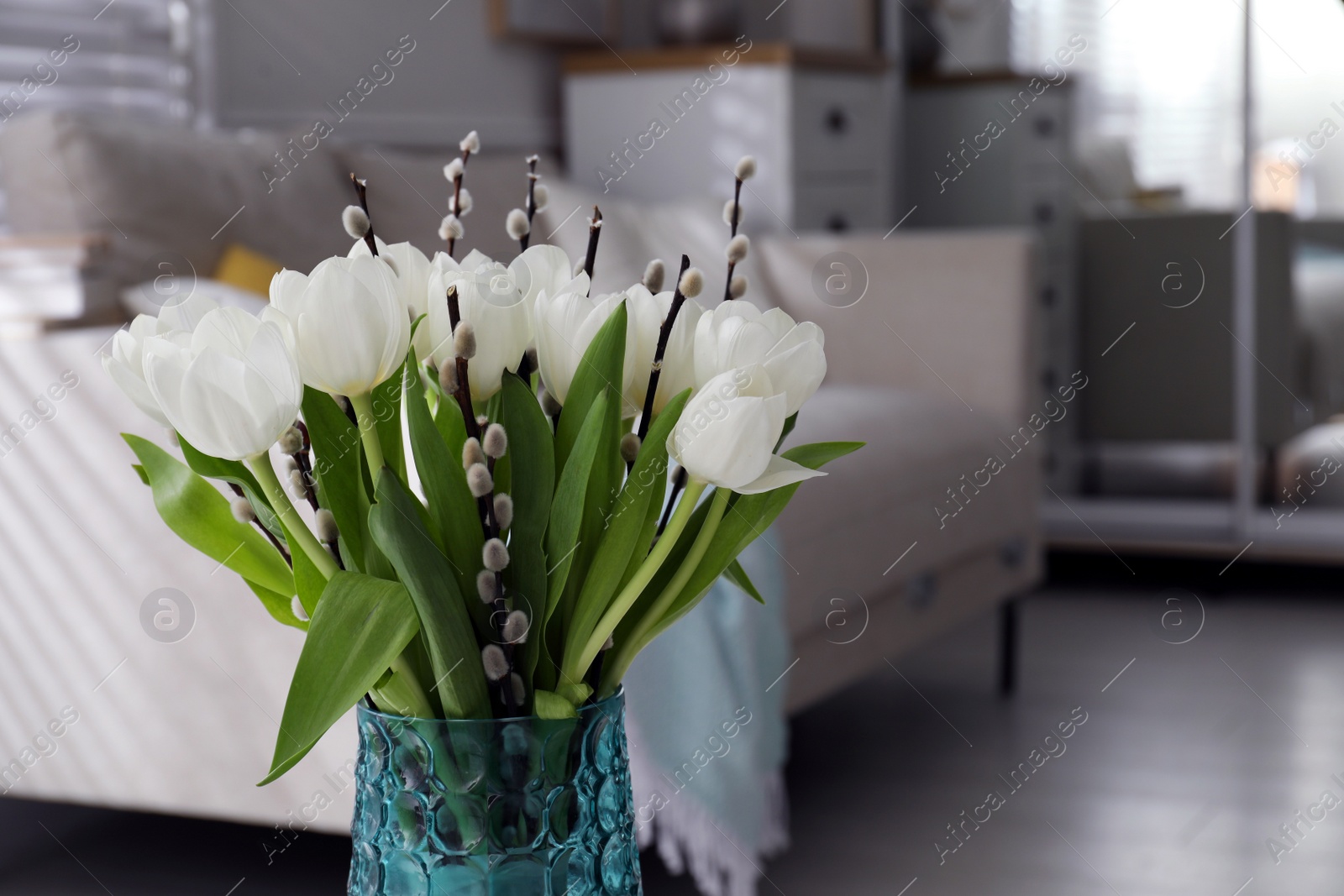 Photo of Beautiful bouquet of willow branches and tulips in vase indoors, space for text