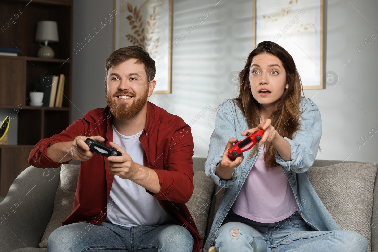 Photo of Couple playing video game with controllers at home