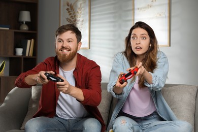 Photo of Couple playing video game with controllers at home