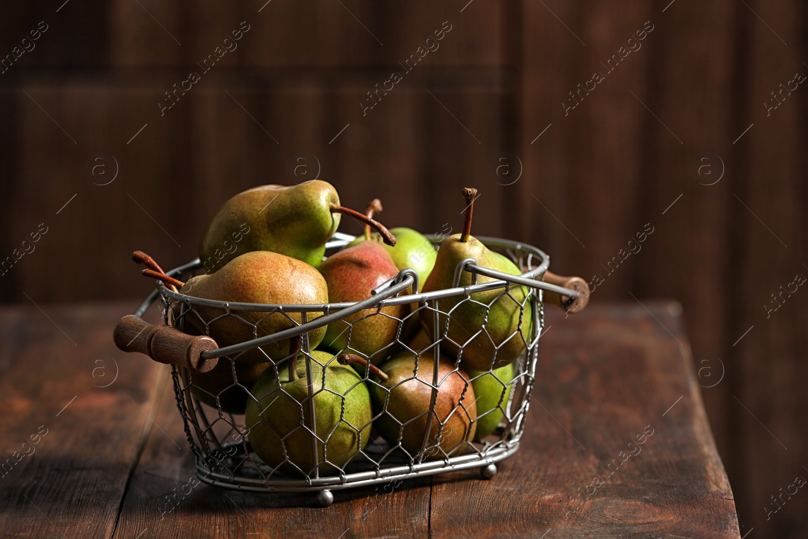 Photo of Basket with ripe pears on wooden table